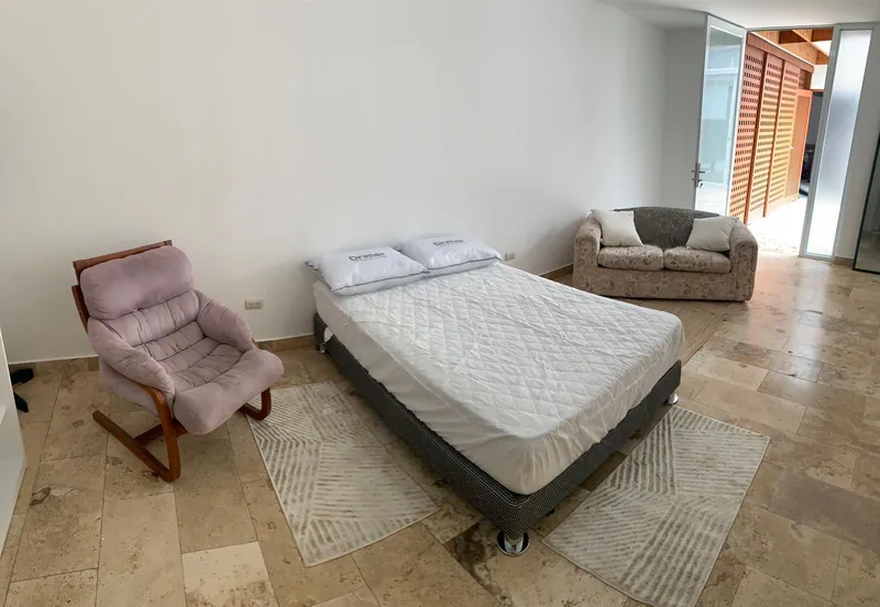 Chambre spacieuse avec lit double, fauteuil et canapé, et une porte ouvrant sur le patio intérieur