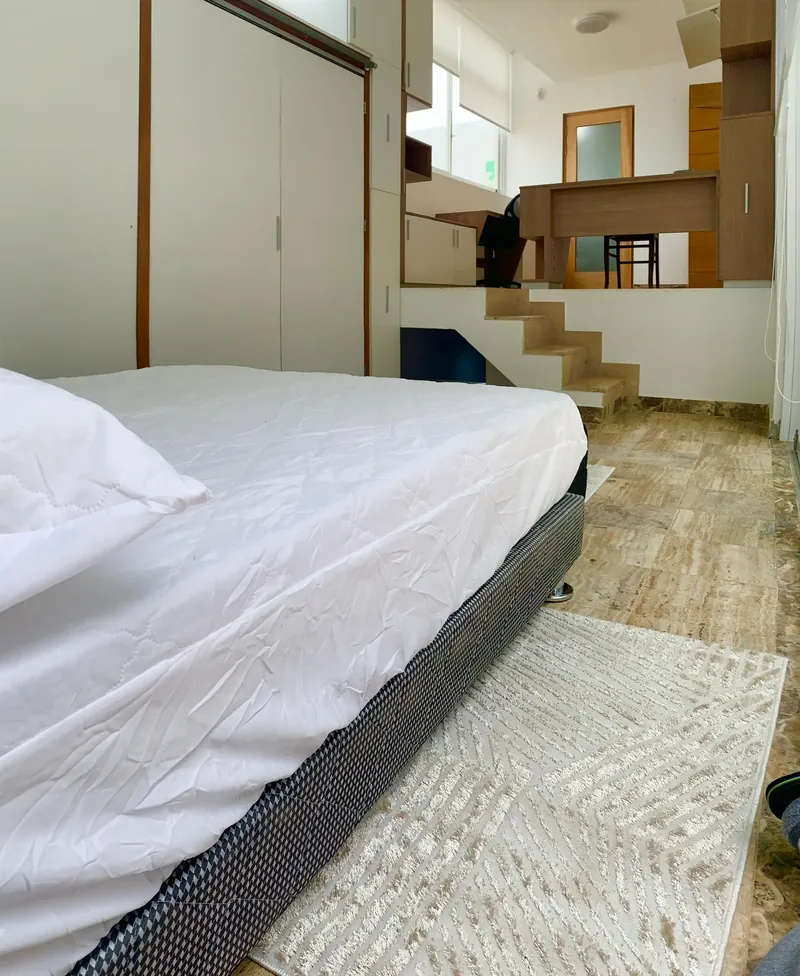 Pièce avec un lit et quelques marches menant à un bureau aménagé en mezzanine