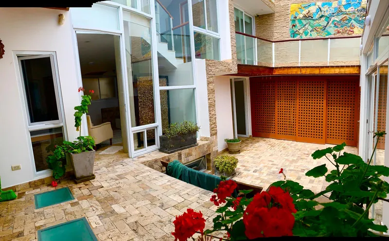 Patio vu d'en haut, avec des dalles de verre dans le sol, des portes à claustra en bois et la fresque en céramique au-dessus